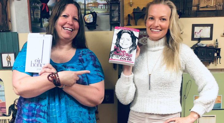 Two women, each holding a copy of each others' book