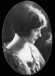 Black and white photo of a woman in profile, looking to her right. She has pale skin and dark curly/frizzy hair.