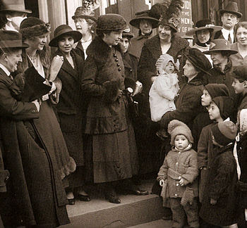 Photo of Margaret Sanger in the middle of a crowd of women and children.